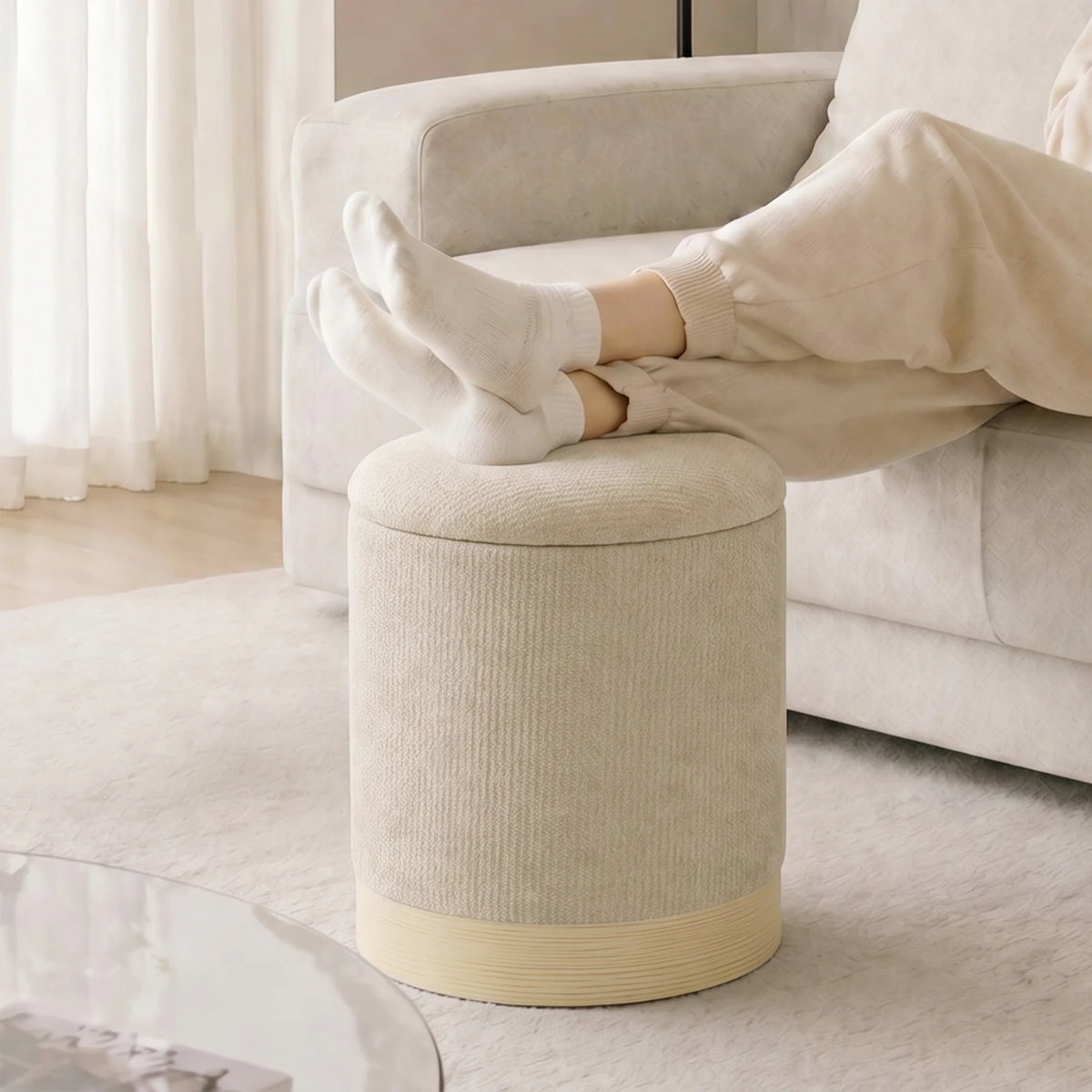 Pouf coffre rond en chenille beige utilisé en repose-pieds