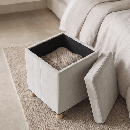 Pouf coffre en velours ouvert, montrant l'espace de rangement avec un plaid