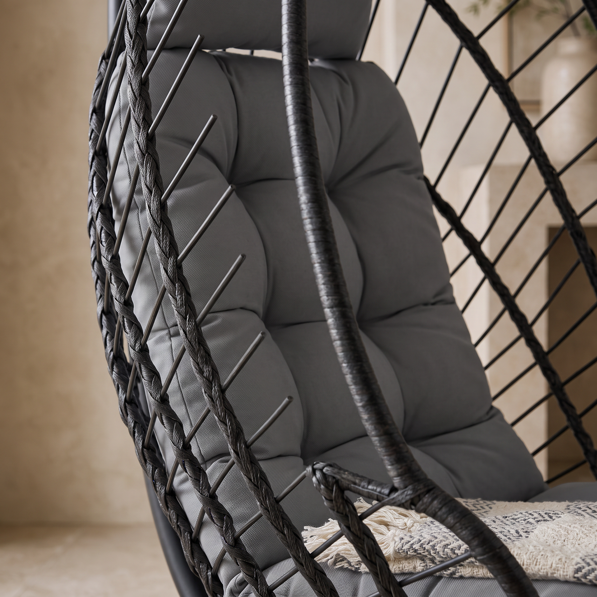 Gros plan sur le panier tressé et le coussin épais du fauteuil œuf suspendu