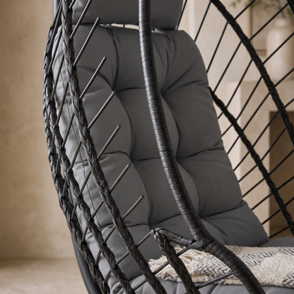 Gros plan sur le panier tressé et le coussin épais du fauteuil œuf suspendu