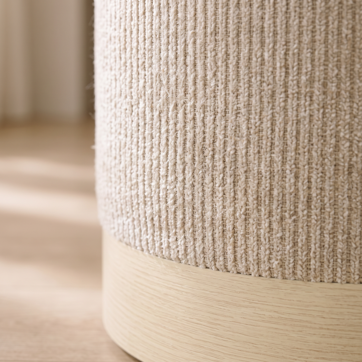 Gros plan sur les côtes de la chenille beige et la base effet bois du pouf coffre rond