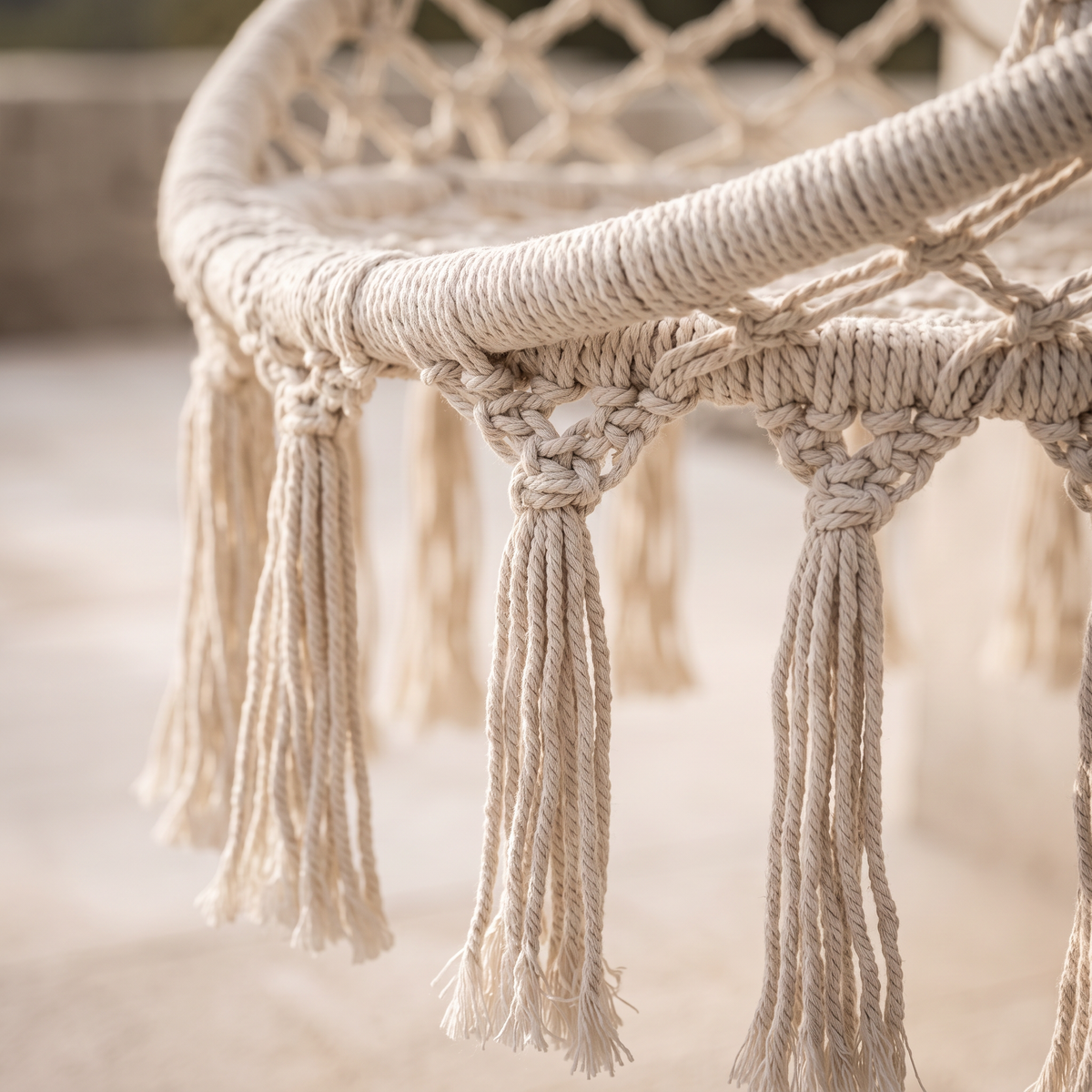 Gros plan sur les nœuds et les franges en coton du fauteuil suspendu en macramé
